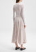 The outfit is shown from a rear three-quarter angle, with the model turned slightly to the side so both the back and a hint of the profile are visible.