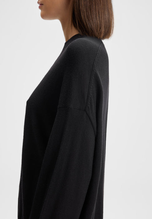 The model is shown in a side profile, facing left. Only the upper torso is visible, with her shoulders relaxed and arms down by her sides, highlighting the fit and drape of the sweater from the side.