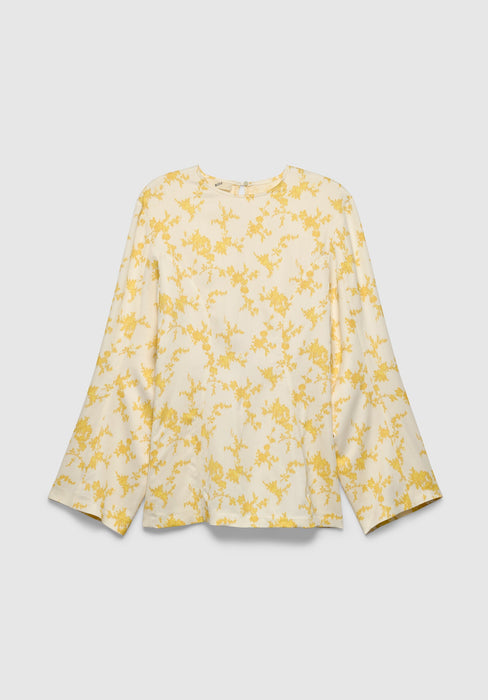 A cream-colored long-sleeve blouse with a relaxed fit, featuring a round neckline and a delicate yellow floral print, displayed against a plain background.