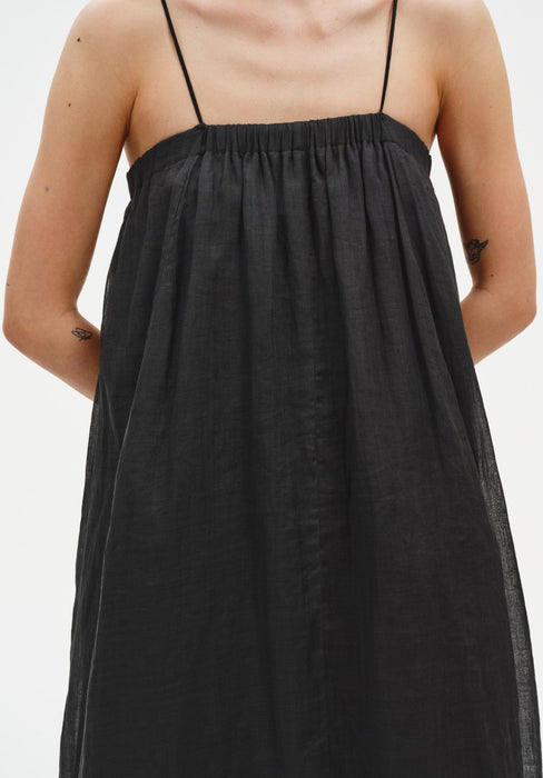 Close-up of a black sleeveless top with thin straps and a gathered neckline, highlighting the soft, lightweight fabric and loose, flowing silhouette.