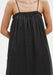 Close-up of a black sleeveless top with thin straps and a gathered neckline, highlighting the soft, lightweight fabric and loose, flowing silhouette.