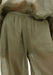 Close-up of lightweight olive-green trousers with a softly gathered waistband, highlighting the semi-sheer, textured fabric and relaxed drape.