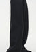 Close-up of black wide-leg trousers highlighting the smooth fabric and a vertical seam running down the leg, showing a clean, structured drape.