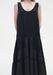 Close-up of a sleeveless black dress featuring a scoop neckline and a softly gathered, semi-sheer panelled skirt with subtle texture.