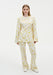 Model wearing a coordinated cream outfit with a yellow abstract floral print, featuring a long-sleeve tunic top with flared cuffs and matching straight-leg trousers, styled with white shoes.