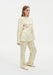 Back view of a model wearing a cream two-piece outfit with a yellow abstract floral print, featuring a long-sleeve tunic top and matching straight-leg trousers.
