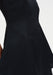Close-up of a black garment highlighting a smooth, structured fabric with a vertical seam and a gently flared silhouette.