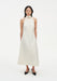 Front view of a model wearing a sleeveless cream midi dress with a high choker-style neckline and A-line silhouette, paired with black pointed shoes against a plain white background.