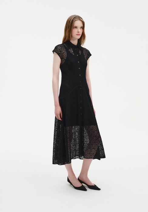 Three-quarter view of a woman wearing a black semi-sheer lace midi dress with a pointed collar, button-down front, and cap sleeves, featuring a fitted bodice and softly flared skirt with sheer lace hem.