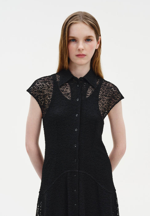 Close-up front view of a woman wearing a black semi-sheer lace dress with a pointed collar, button-down front, and cap sleeves, highlighting the delicate lace texture and panel detailing.